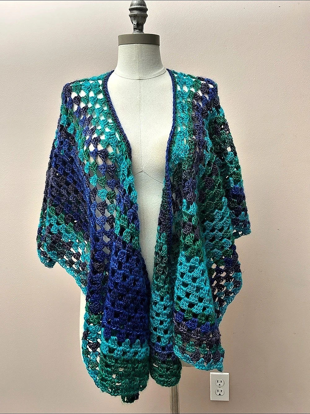 handmade crochet open-stitch wrap or shawl in a gradient blend of blue, teal, an